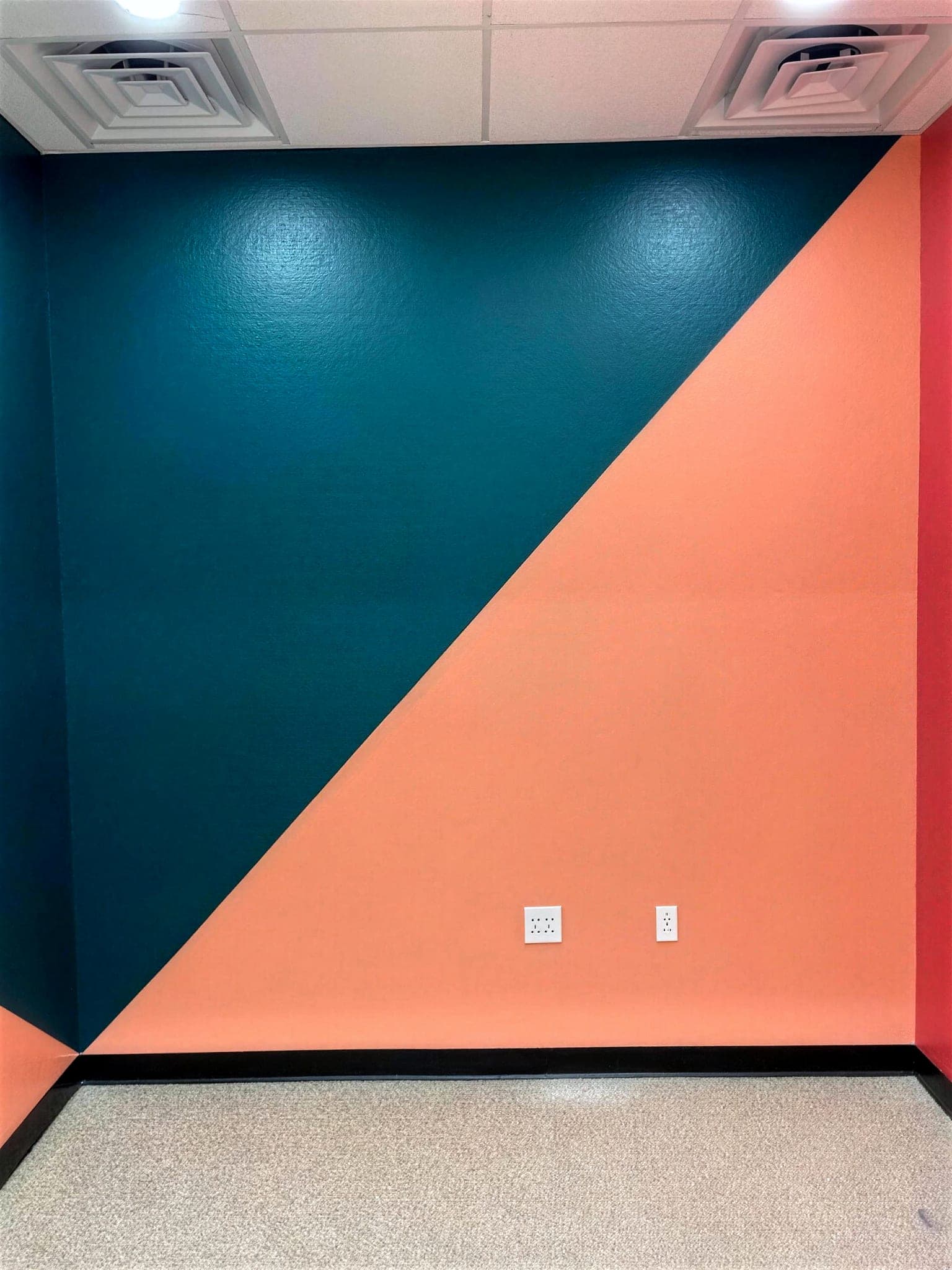 Commercial room with a diagonal teal and coral painted accent wall.