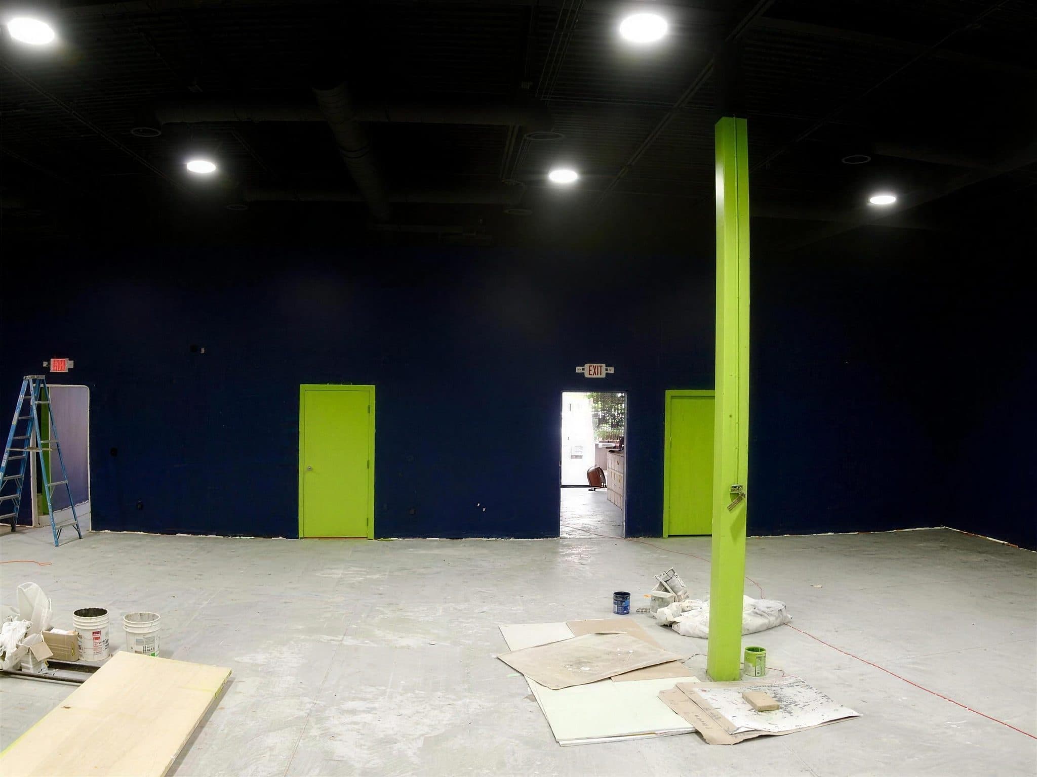 Navy wall with two lime green doors, an exit doorway and a lime green steel column at Pulze gym.