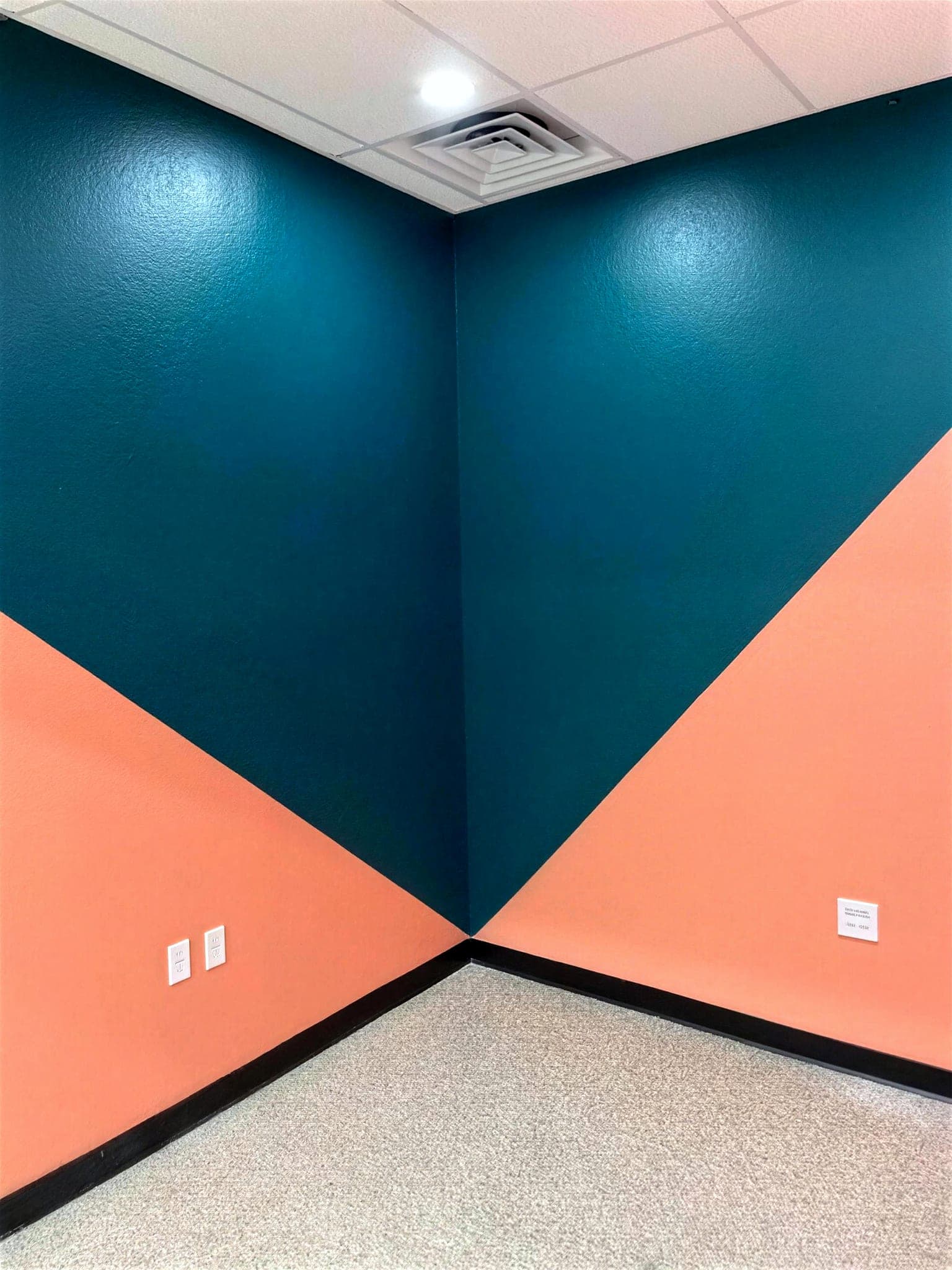 Corner of a commercial room painted teal and coral.