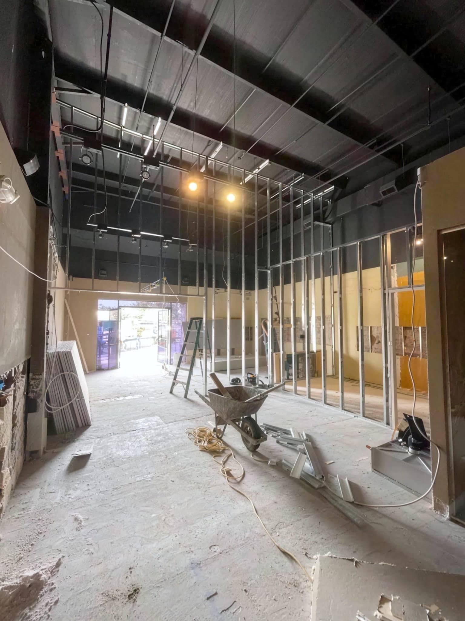 Commercial suite mid build-out with new metal stud walls, an open ceiling and debris on the floor.