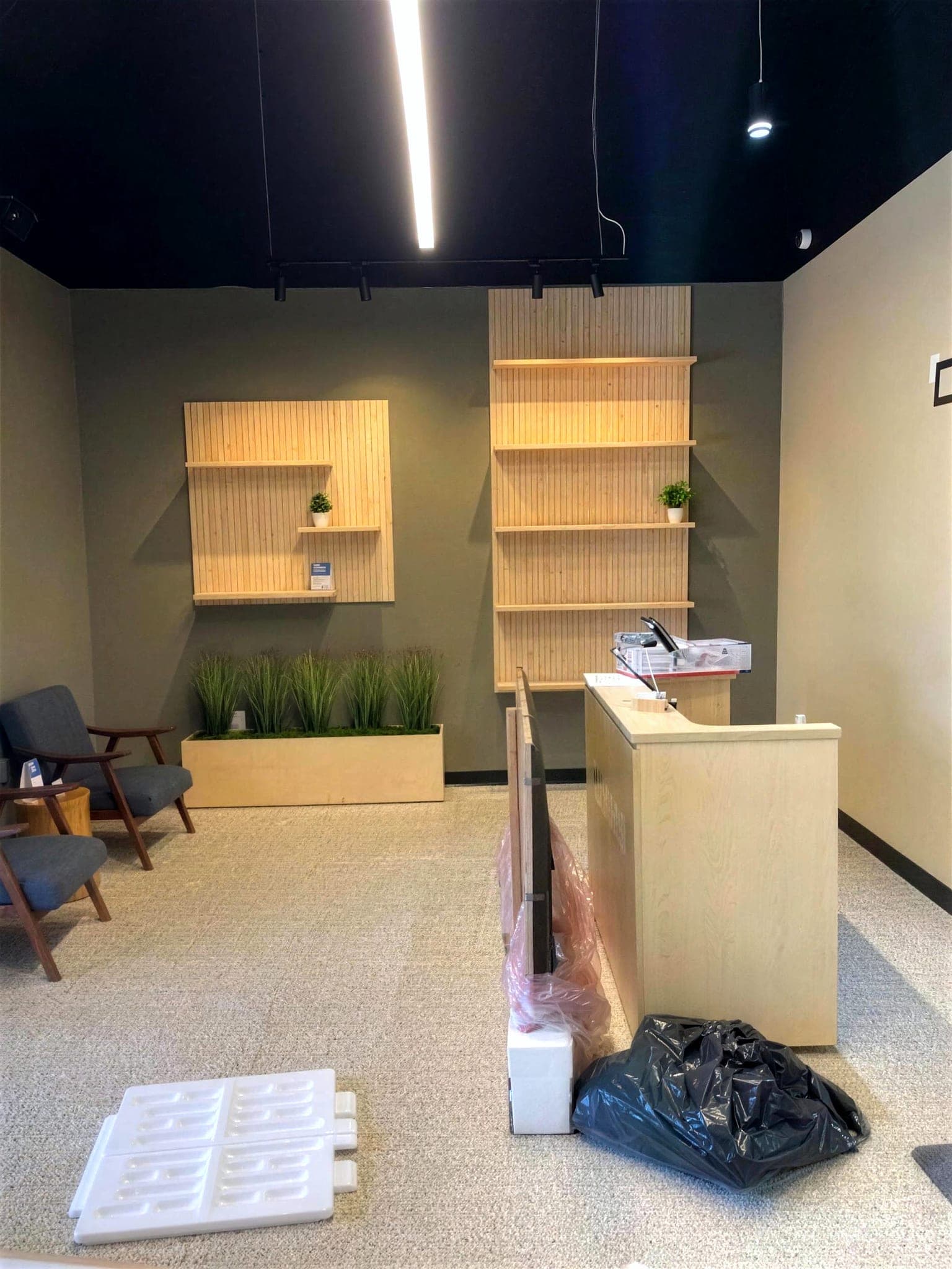 Finished reception area with a flake epoxy floor, a light wood front desk and wall shelving.