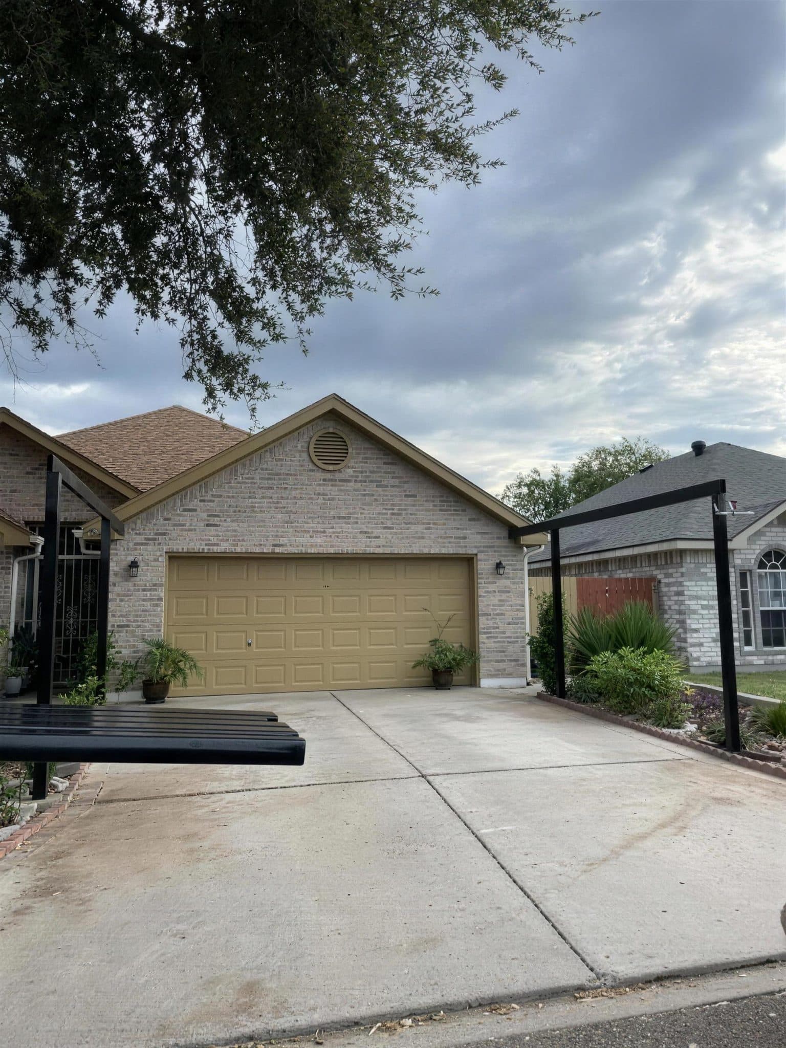 Open concrete driveway in front of a brick house and garage before the carport