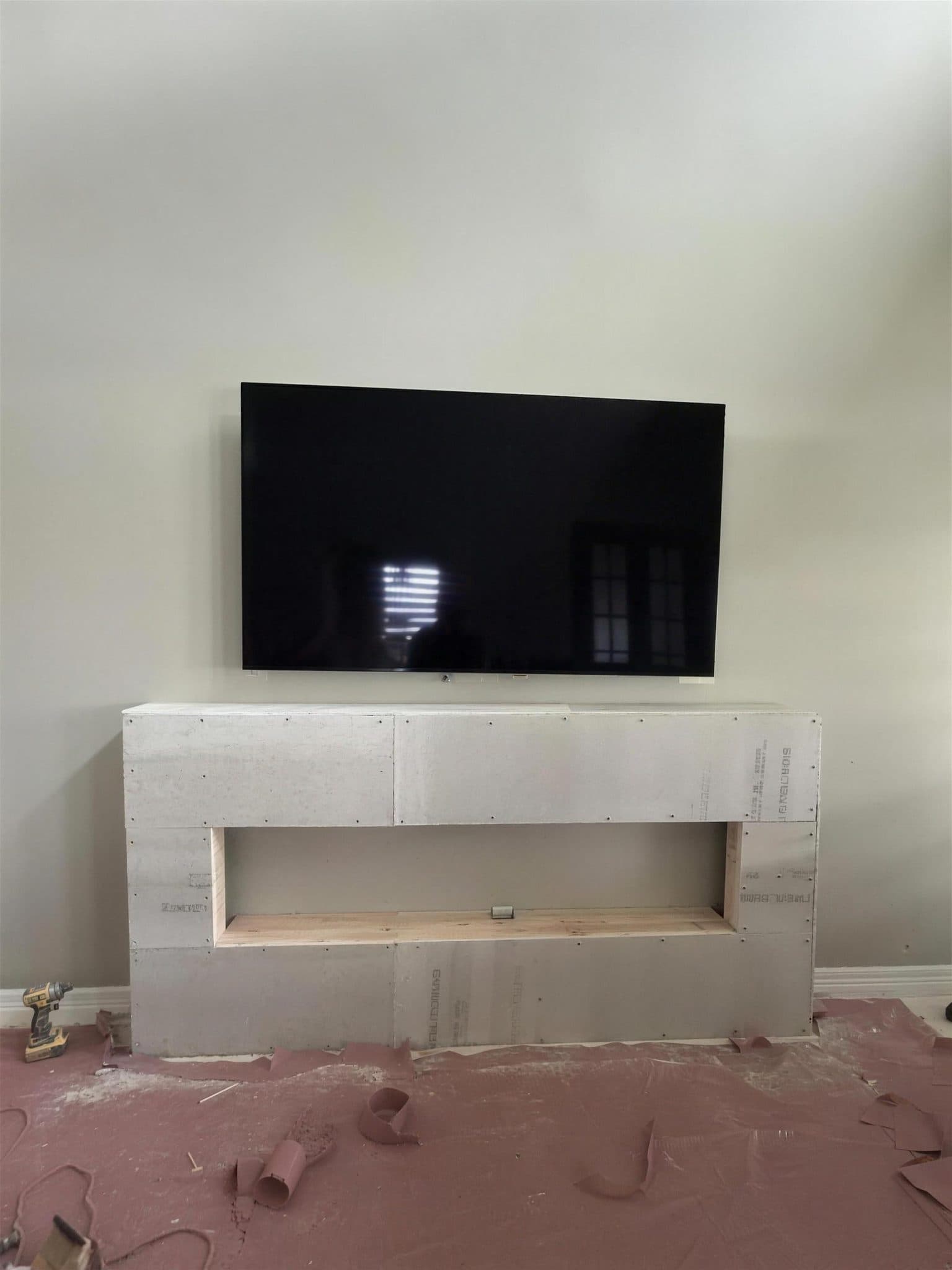 Framed fireplace box sheathed in cement board under the TV, with the firebox opening cut in