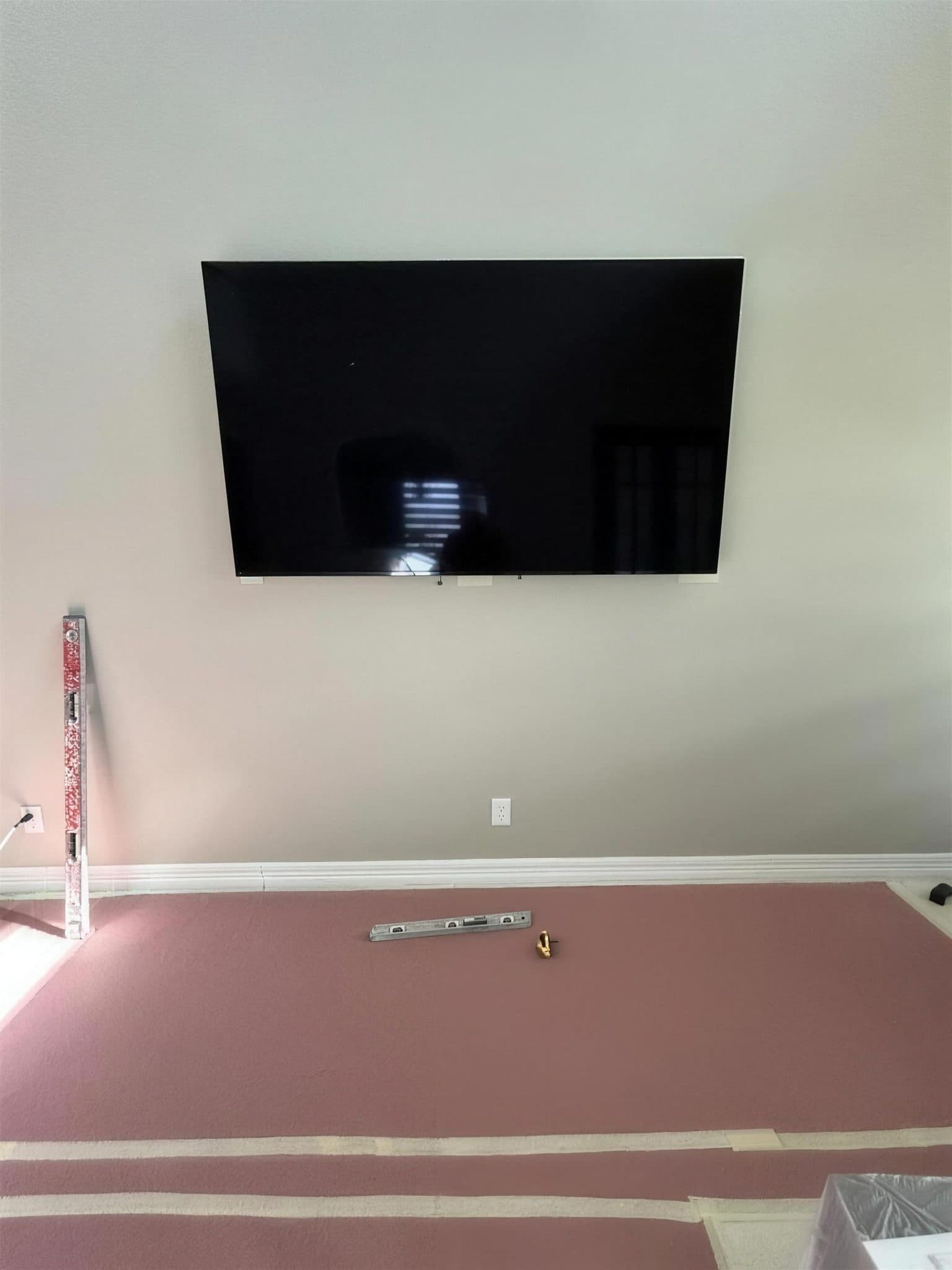 Living room wall with a mounted TV above a bare floor covered in protective paper before the fireplace build