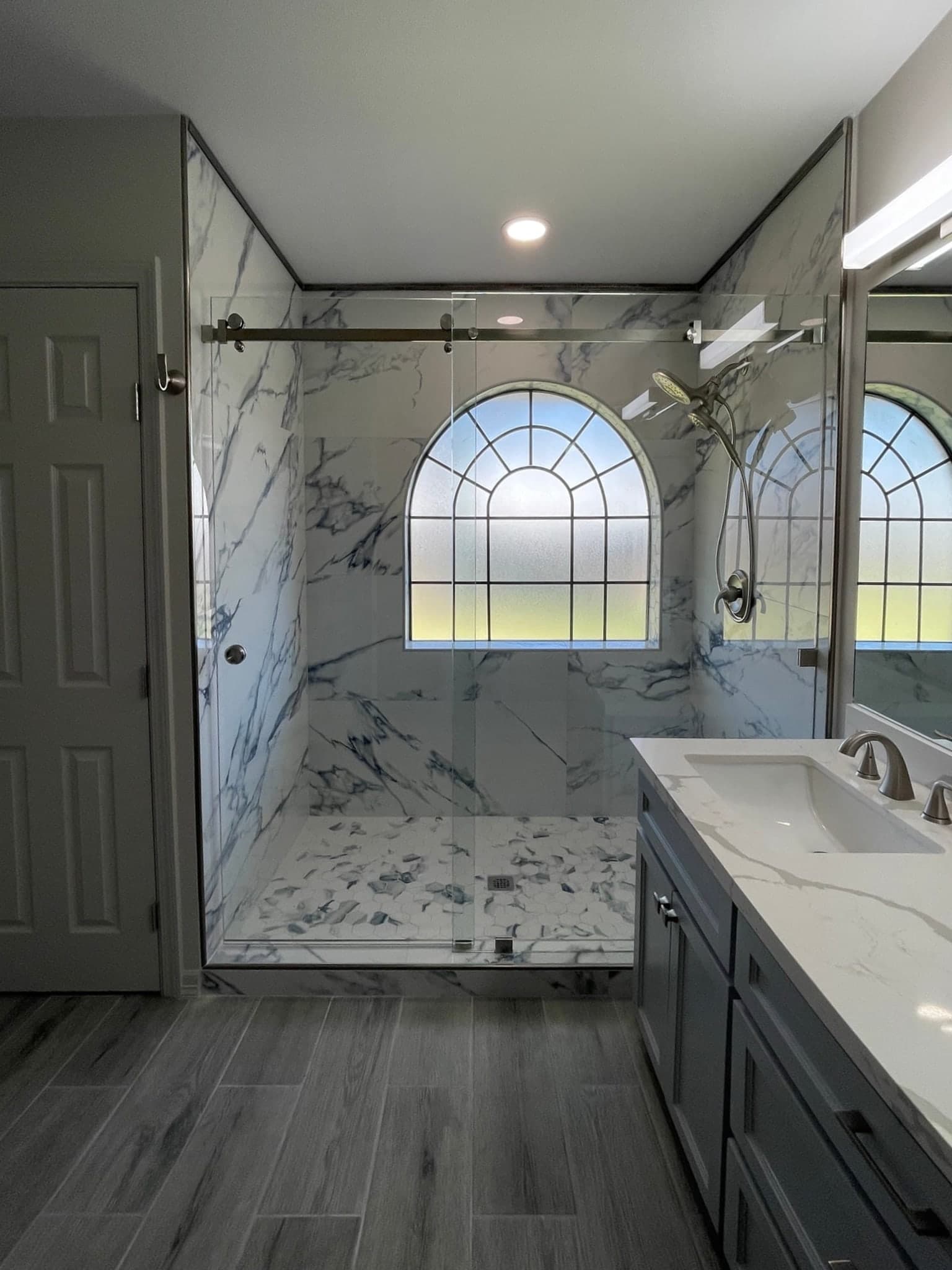 Modern master bathroom featuring a marble walk-in shower with glass doors and a double vanity.