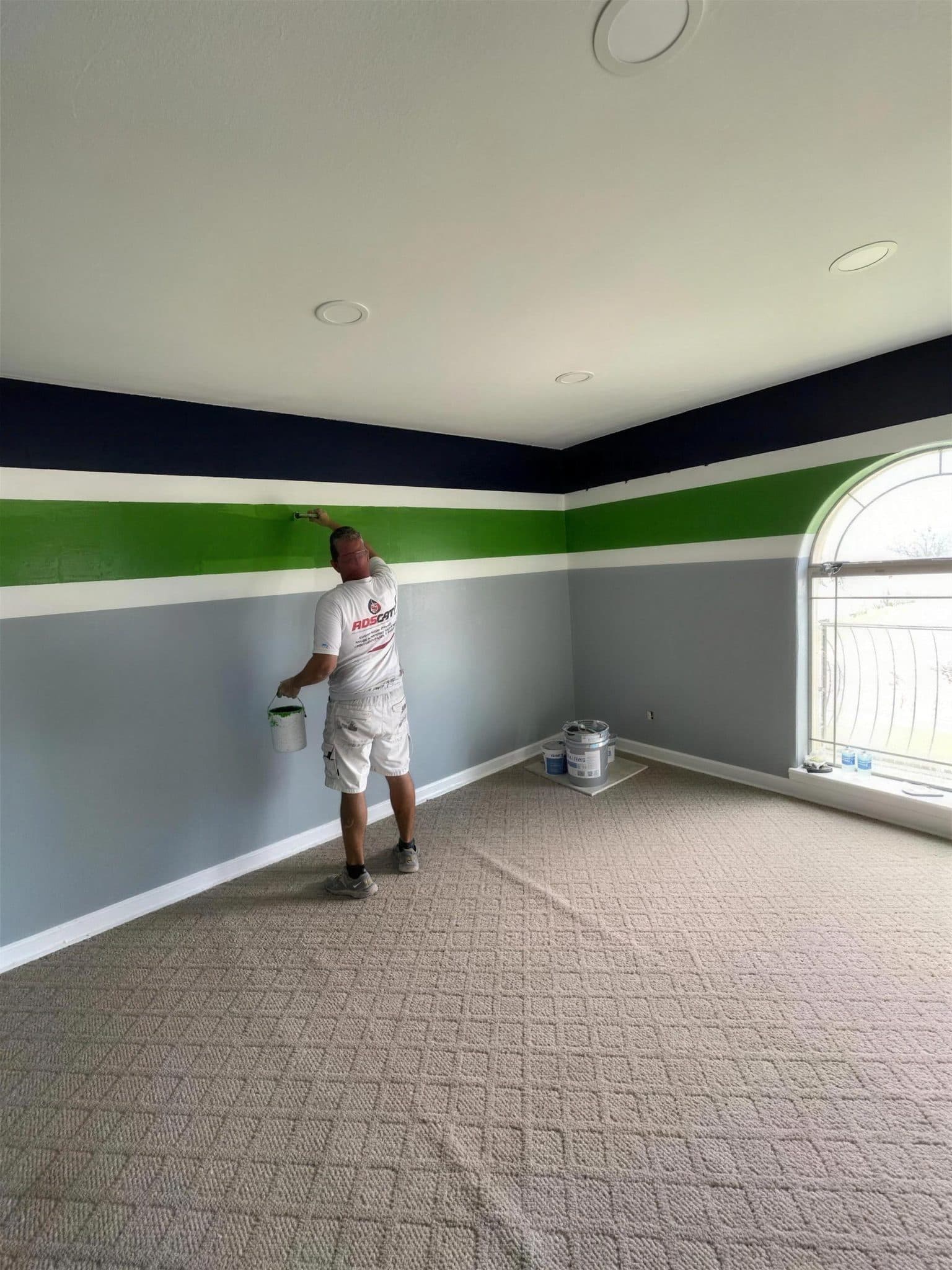 Painter working on navy, green and gray striped walls