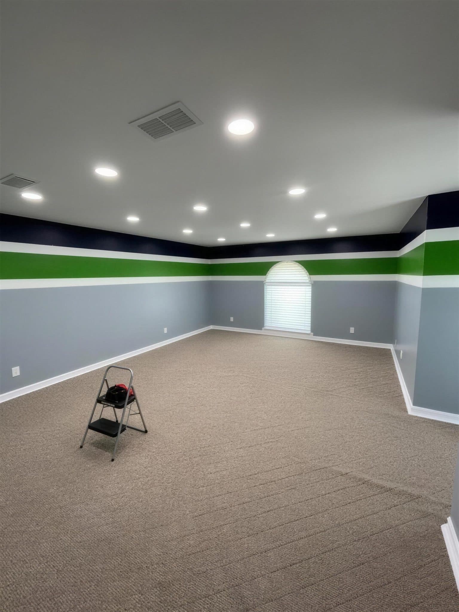 Finished room with navy, green and gray striped walls seen from the far corner