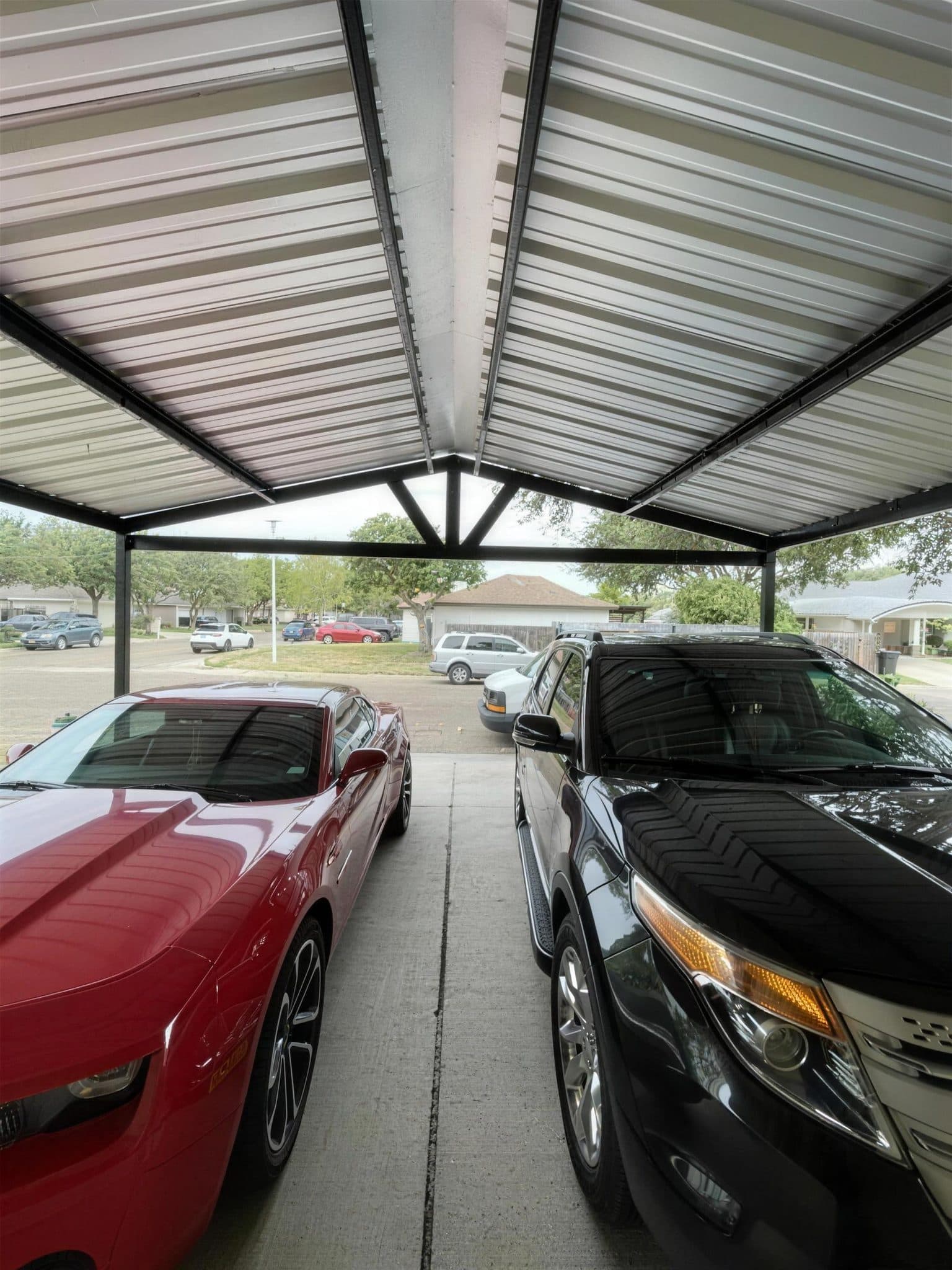 View from under the new steel carport with two cars parked on the driveway