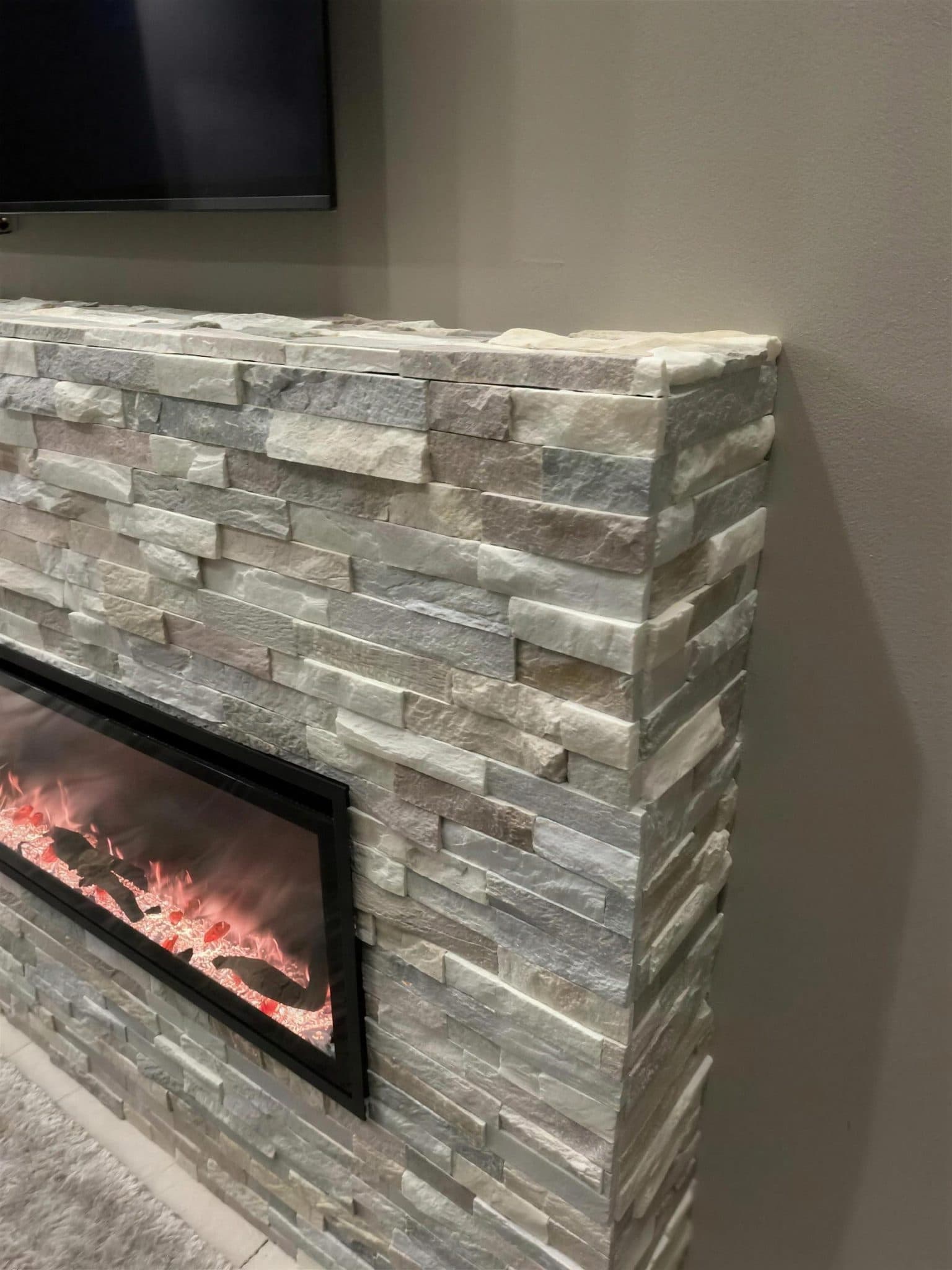 Corner detail of the stacked stone veneer wrapping the fireplace surround