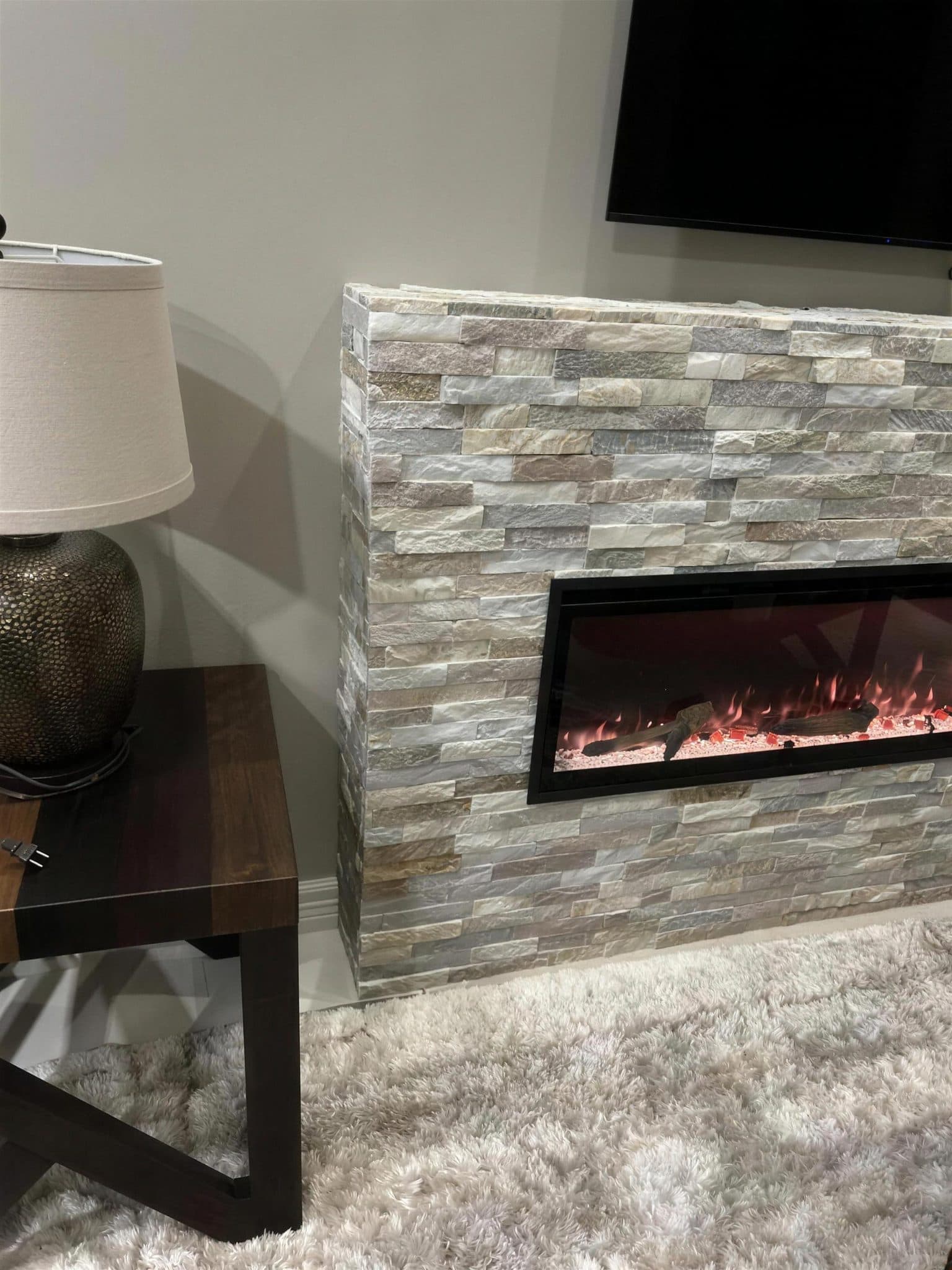 Side view of the stacked stone fireplace surround beside an end table and lamp